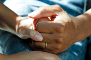 Two hands shown in a supportive grip resting on blue denim, reflecting the need for support if you’ve faced medical malpractice or a doctor's error.