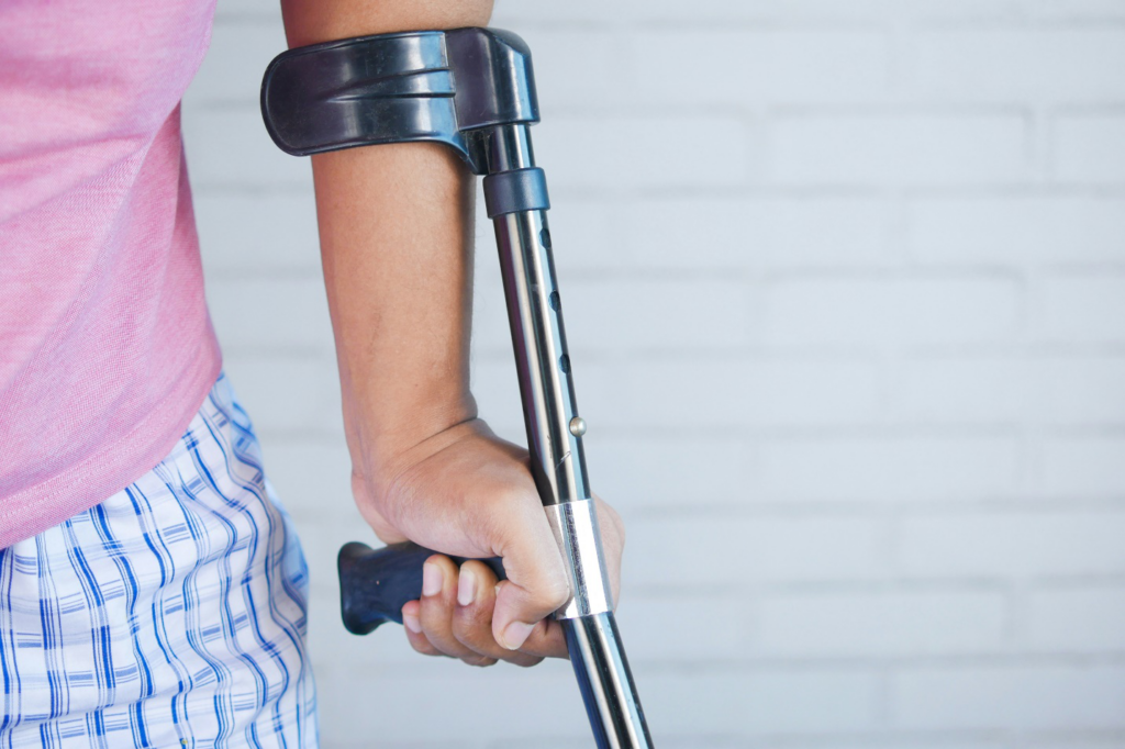 Close-up of a person's arm holding a metal crutch, reminding us that the cost of medical equipment can be covered if one takes up the offer of a free consultation with a personal injury lawyer.