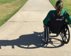 A person in a black wheelchair with the text "drive" written in white on a cemented path with grass on either side, representing how a free consultation with a personal injury lawyer could help victims of personal injury pay for adjustments required to live a near-normal life.