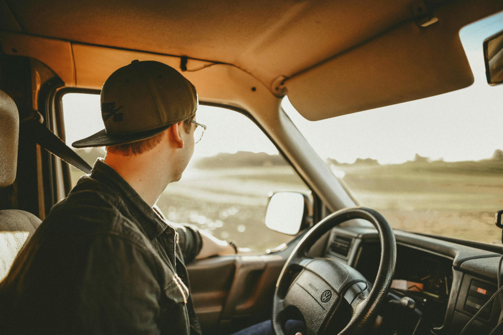 Three large white trailer trucks stand one behind the other with dense foliage in the background, highlighting how trucks play a vital role in moving goods across the country, making it all the more important to have lawyers for truck drivers on hand.