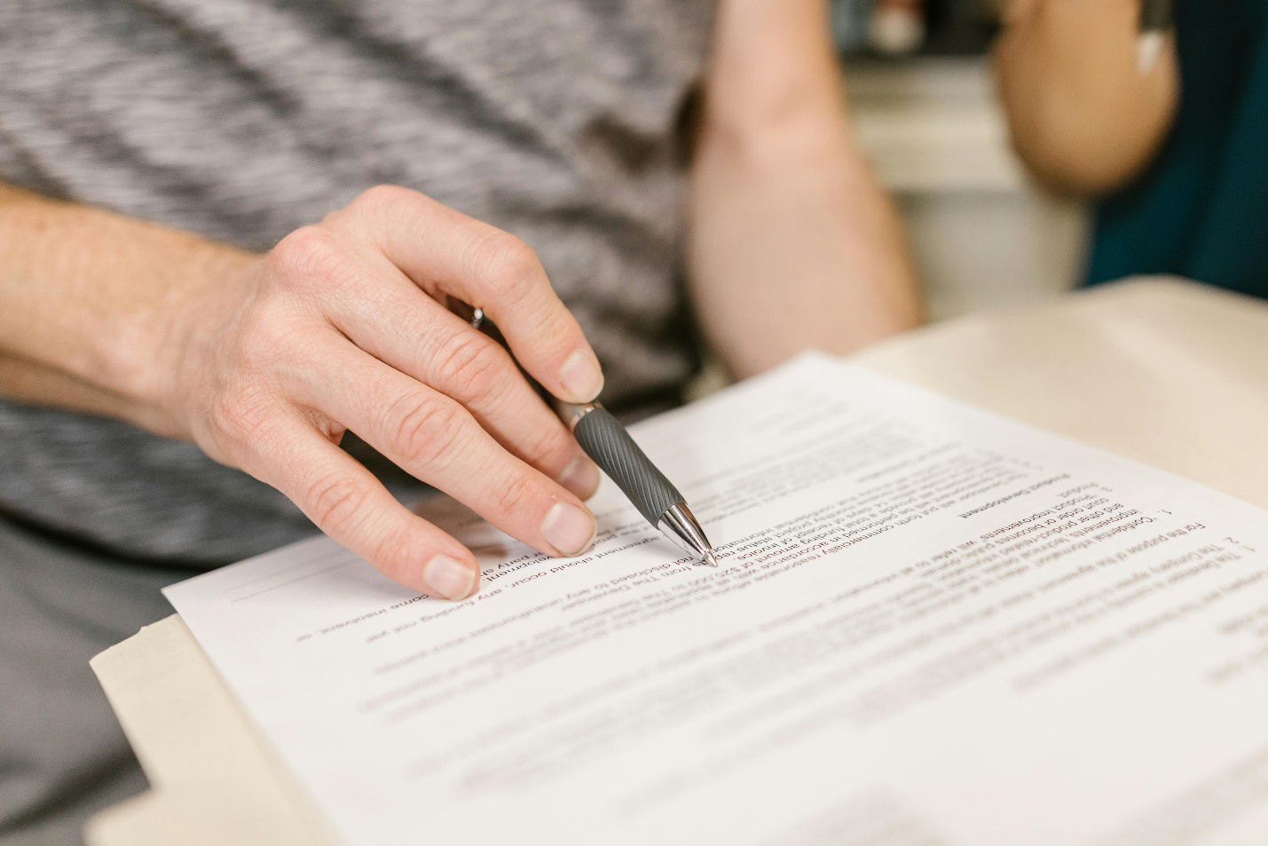 a person pointing a pen at a piece of document