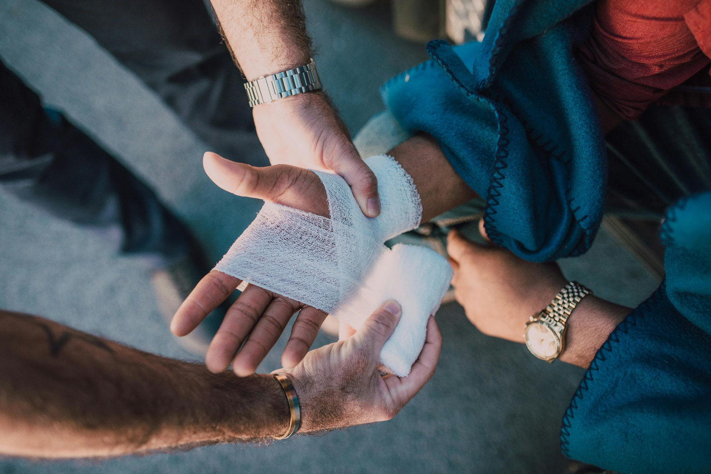 a person wrapping a bandage on another’s hand