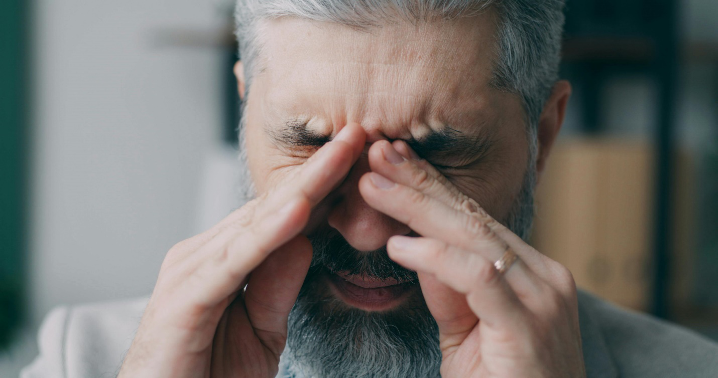 man pressing eyes with his hands in stress